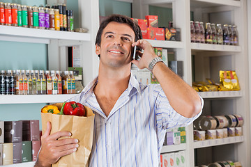 Image showing Man With Paper Bag Using Cellphone In Market