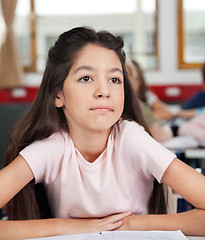 Image showing Thoughtful Schoolgirl Looking Away While Sitting At Desk