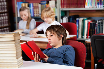 Image showing Relaxed Schoolboy Reading Book In Library