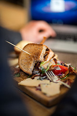 Image showing Half Eaten Sandwich On Wooden Plate