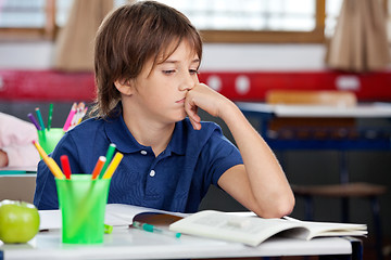 Image showing Schoolboy Looking At Book In Classroom