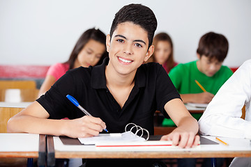 Image showing Teenage Schoolboy Writing In Binder At Desk