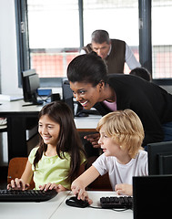 Image showing Teacher Assisting Schoolchildren In Using Desktop Pc