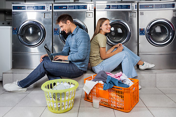 Image showing Couple Using Laptop And Earphones At Laundry