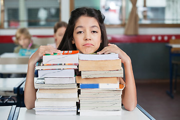 Image showing Sad Schoolgirl Resting Chin On Stacked Books At Desk