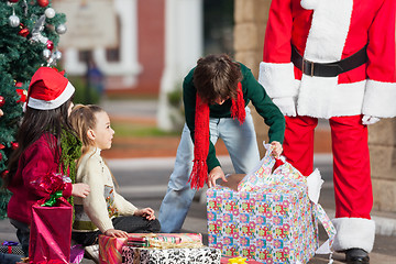 Image showing Boy Opening Christmas Present In Courtyard