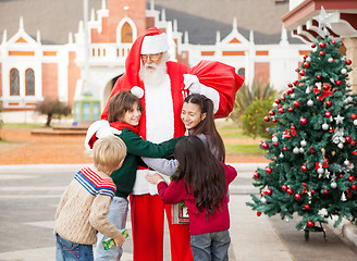 Image showing Children Embracing Santa Claus