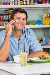 Image showing Man Using Cellphone At Table In Supermarket