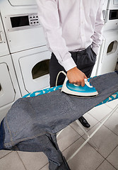 Image showing Businessman Ironing Jeans In Laundry