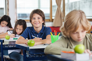 Image showing Schoolboy Sitting At Desk With Classmates In A Row