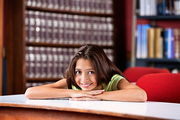 Image showing Happy Schoolgirl Resting Chin On Hands At Table In Library