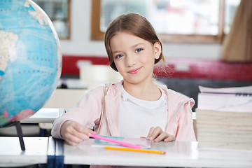 Image showing Schoolgirl Smiling With Books And Globe At Desk