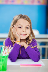 Image showing Cute Girl Sitting With Hand On Chin At Desk