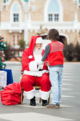Image showing Santa Claus Holding Boy's Hands