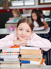 Image showing Happy Schoolgirl Leaning On Stacked Books At Desk