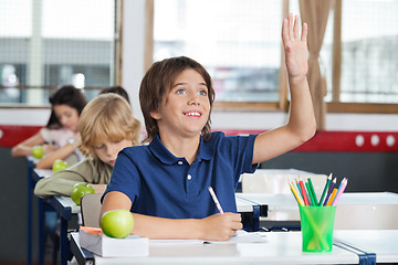 Image showing Schoolboy Raising Hand While Sitting At Desk