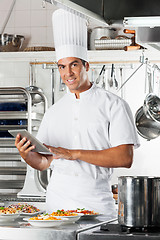 Image showing Young Chef Holding Tablet With Pasta Dishes At Counter