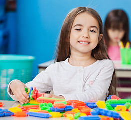 Image showing Girl Playing With Construction Blocks With Friends In Background