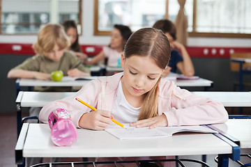 Image showing Schoolgirl Drawing In Book At Classroom