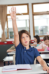 Image showing Cute Schoolboy Raising Hand In Classroom