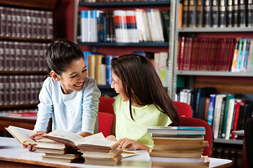 Image showing Happy Schoolgirls Looking At Each Other While Studying In Librar