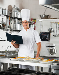 Image showing Chef With Book Standing By Kitchen Counter