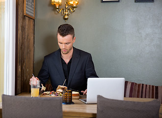 Image showing Businessman Having Sandwich At Restaurant