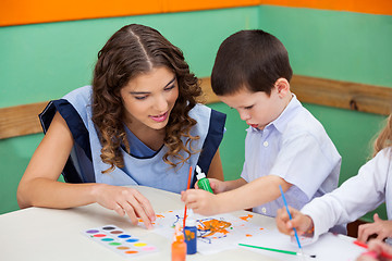 Image showing Boy Painting While Teacher Assisting Him