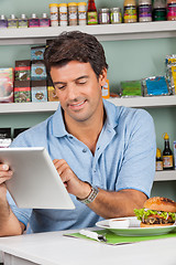 Image showing Male Customer With Snacks Using Digital Tablet In Store