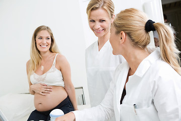 Image showing Doctors Looking At Each Other With Pregnant Woman In Clinic