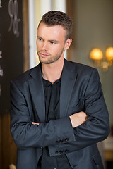 Image showing Thoughtful Businessman Standing Arms Crossed In Coffeeshop