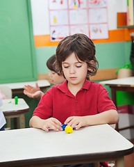 Image showing Boy Molding Clay While Friends Playing In Background