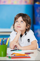 Image showing Boy Looking Up While Sitting With Hand On Chin At Desk