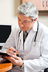 Image showing Mature Doctor Reading At Desk
