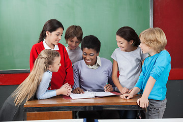Image showing Female Teacher Teaching Schoolchildren At Desk