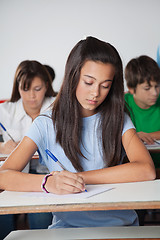 Image showing Female Student Writing Paper At Desk In Classroom