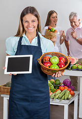 Image showing Saleswoman Holding Digital Tablet And Fruits Basket
