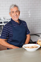 Image showing Senior Salesman With Plate Of Biscuits At Counter