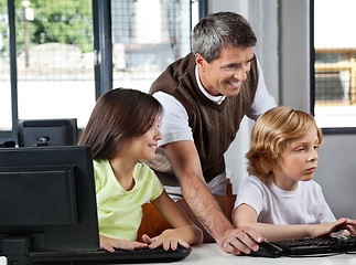 Image showing Teacher Assisting Schoolchildren In Using Desktop Pc