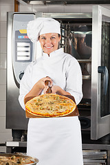 Image showing Confident Female Chef Presenting Pizza