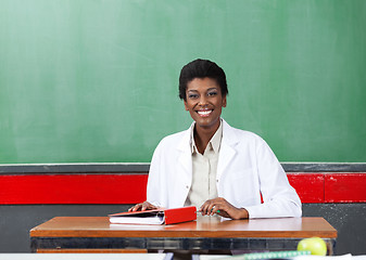 Image showing Portrait Of Happy Teacher Sitting At Desk In Classroom
