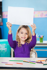 Image showing Girl Holding Blank Paper At Desk In Classroom