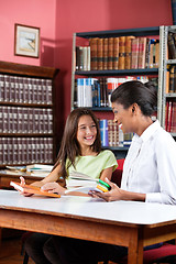 Image showing Librarian Teacher And Schoolgirl Looking At Each Other In Librar