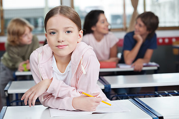 Image showing Schoolgirl Leaning On Desk With Students In Background