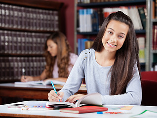 Image showing Teenage Schoolgirl Writing In Book At Table