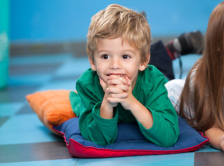 Image showing Boy With Hands Clasped Lying On Floor In Kindergarten