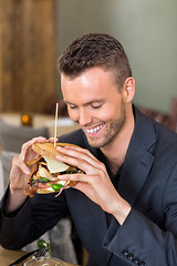 Image showing Businessman Holding Sandwich In Coffeeshop