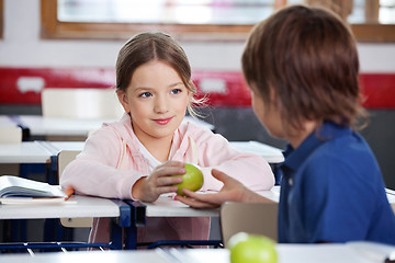 Image showing Little Girl Giving Apple To Boy In Classroom