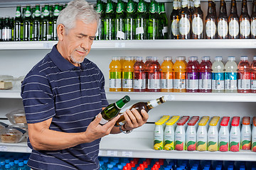 Image showing Senior Man Comparing Beer Bottles