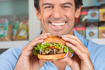 Image showing Happy Man Holding Bugger In Grocery Store